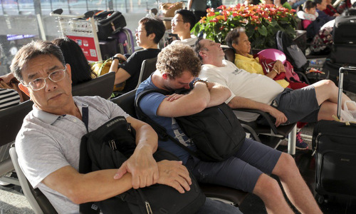 Hành khách ngồi chờ tại sân bay Hong Kong sáng 13/8. Ảnh: SCMP.