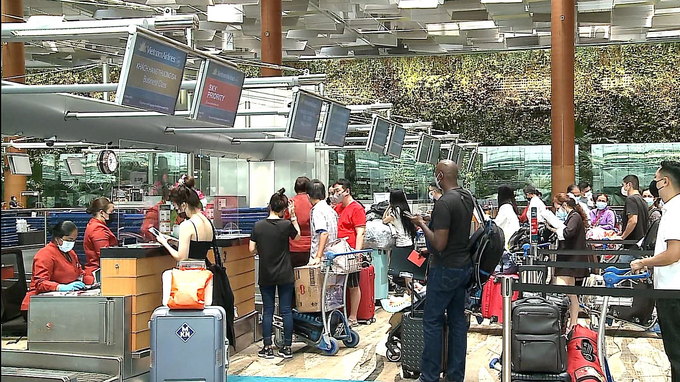 Các vị khách nước ngoài làm thủ tục lên chuyến bay VN 650 đến TP.HCM tại Singapore
