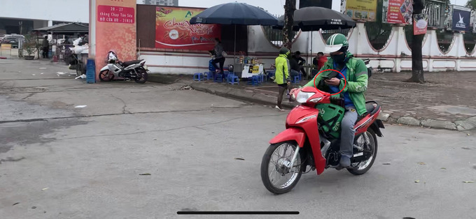 Tài xế Grab Food một tay chạy xe một tay lướt điện thoại trên đường Phạm Hùng, Hà Nội.