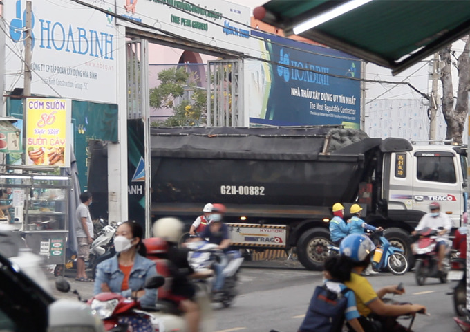 Những chiếc xe chở bùn đất có ngọn ở dự án The Peak Garden ì ạch lưu thông ra  đường Phạm Hữu Lầu, Quận 7. 