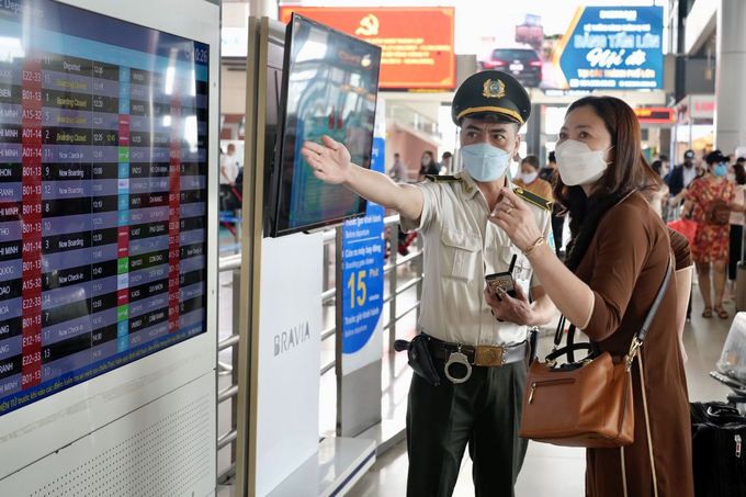 Nhân viên An ninh hàng không hướng dẫn khách cách xem thông tin chuyến bay trên màn hình thông báo bay (FIDS)
