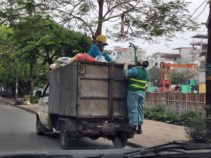 Xe thu gom, vận chuyển rác của Công ty CP Môi trường đô thị Thanh Trì không chỉ hoạt động trong khung giờ cao điểm mà còn để công nhân ngồi trên thùng xe, thậm chí đu bám phía sau gây mất ATGT.