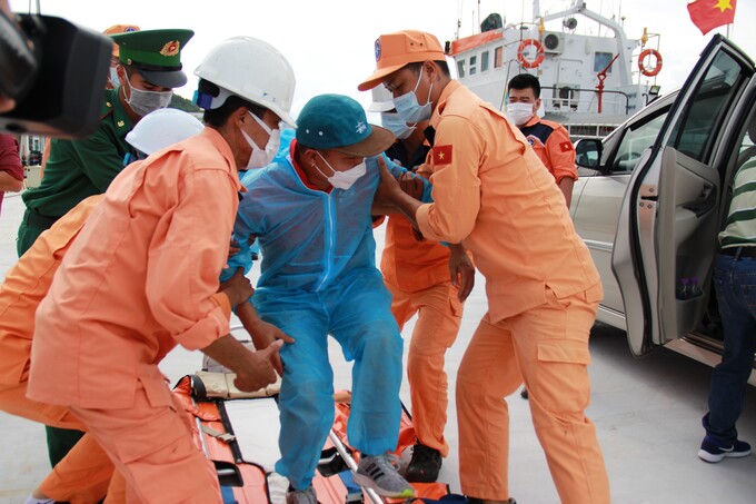 Sau khi lên bờ, thuyền viên được lực lượng cứu hộ dìu lên xe để đi điều trị