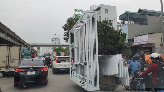 Xe ba bánh tự chế chở theo biển quảng cáo dài hơn thân xe cả mét trên đường Nguyễn Xiển, Hà Nội.
