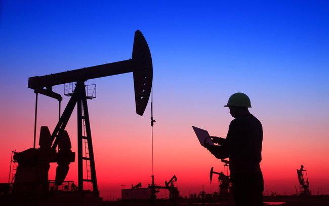 oil-field-worker-with-a-laptop-at-sunset-156021771