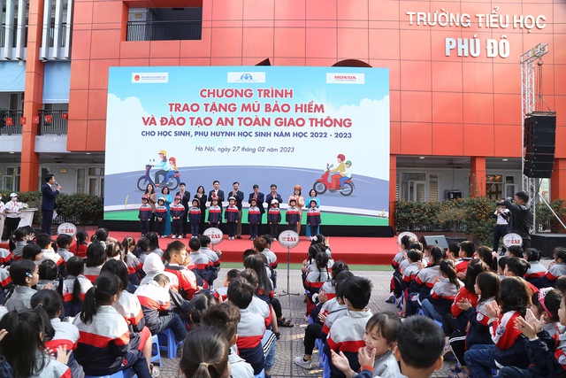 Đại diện Honda Việt Nam và Ủy ban ATGT Quốc gia trao tặng mũ bảo hiểm cho các em học sinh.