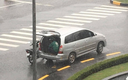 Ôtô dừng bên góc đường mở cửa cho tài xế xe ôm ngồi trú mưa