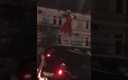 Cô gái mặc váy đỏ leo lên nóc ô tô nhảy múa điên cuồng