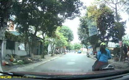 Người phụ nữ dừng xe máy nghe điện thoại trước đầu ôtô
