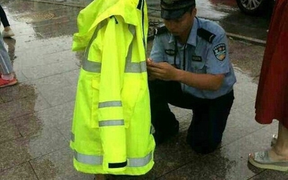 Hình ảnh cảnh sát dầm mưa nhường áo cho em bé đi lạc