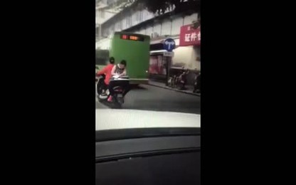 Nữ sinh Trung Quốc ngồi ngược sau xe máy làm bài tập